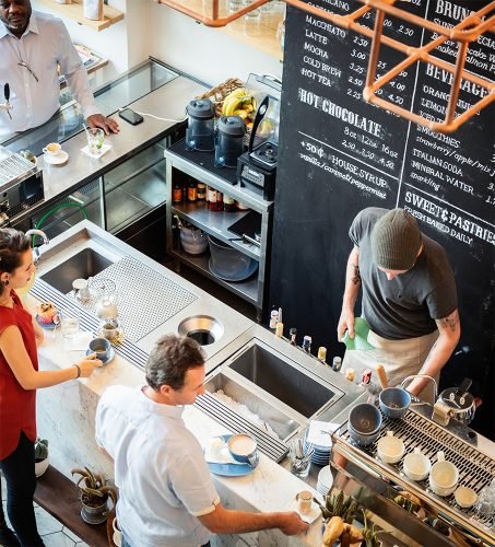 Top view of cafe with diverse people ordering coffee. Customers and baristas at the counter. Coffee shop with barista and customers. Busy coffee shop scene. Men and women ordering coffee at counter